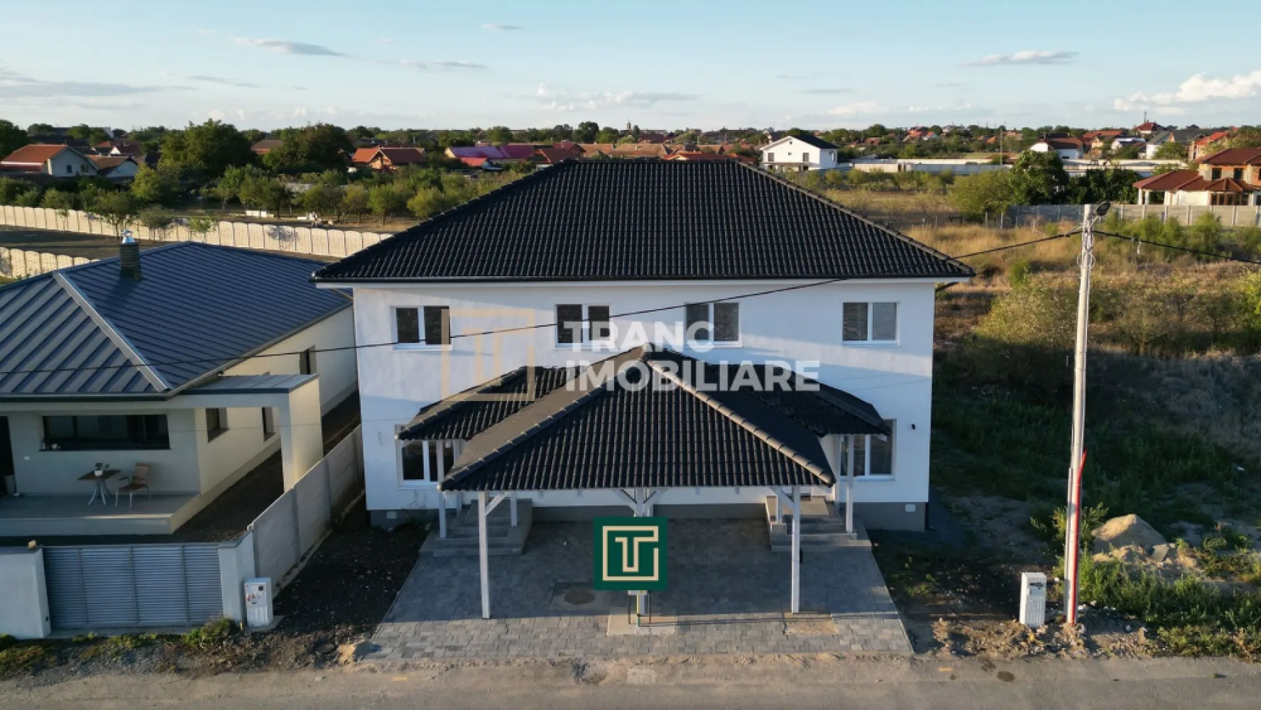Jumătate de duplex nou cu 4 camere in Vladimirescu - În Vladimirescu, într-o zonă liniștită, dar cu acces rapid la centura Aradului, Tranc Imobiliare vă oferă la vânzare o locuinta formata din jumatate dintr-un duplex nou, finalizat în 2025 și pregătit să fie locuit imediat. Locuința se predă la cheie, nemobilată, cu finisaje moderne și de calitate superioara, gândite pentru a oferi un ambient elegant și ușor de personalizat de către viitorii proprietari.

Suprafața construită este de 154 mp, iar cea utilă de 96 mp, desfășurată pe parter, mansardă și pod. Terenul are 342 mp, cu un front stradal de 8 metri și acces direct din drum asfaltat. Compartimentarea este practică și bine gândită: living luminos, bucătărie spațioasă, trei dormitoare, două băi complet funcționale, o terasă acoperită de 7,6 mp, dar și o cameră tehnică situată sub scară, unde se află centrala termică și spațiu suplimentar pentru depozitare și mașina de spălat. În fața casei, proprietarii beneficiază de o parcare acoperită de 18 mp.
Finisajele interioare sunt moderne și luminoase, cu pardoseli din parchet și gresie în tonuri calde, pereți zugrăviți cu lavabil alb, plinte elegante, uși interioare albe cu design contemporan și băi complet amenajate cu faianță de bun gust. Totul este nou și pregătit pentru a fi folosit din prima zi.

Din punct de vedere tehnic, casa este solid construită, cu pereți din cărămidă, fundație de beton și acoperiș din țiglă ceramică. Izolația exterioară din polistiren de 10 cm asigură eficiență energetică, iar instalațiile electrice din cupru și cele sanitare din PPR oferă durabilitate. Încălzirea se realizează prin centrală pe gaz, cu incălzire în pardoseală. Proprietatea este racordată la toate utilitățile, apă, gaz, curent trifazic, canalizare.
Chiar dacă dormitoarele sunt mai compacte, avantajele acestei proprietăți, prin faptul că este o construcția nouă, finisajele sunt moderne, are eficiența energetică ridicată și zona este liniștită, dar totuși aproape de centură si de zona centrală a satului Vladimirescu, o transformă într-o alegere foarte bună atât pentru locuință permanentă, cât și ca investiție.

Curtea poate fi transformată într-o grădină verde, cu gazon, flori și arbori, sau într-un spațiu de relaxare cu foișor și loc de grătar. Pentru familiile cu copii, terenul poate deveni loc de joacă privat, iar pentru cei care apreciază confortul, există suficient spațiu pentru o piscină mică ori o zonă de terasă extinsă. Astfel, cumpărătorul nu achiziționează doar o locuință modernă, ci și libertatea de a-și crea propriul colț de liniște și confort după dorințe.

Această locuința este soluția ideală pentru o familie care își dorește o casă nouă, bine compartimentată și gata de locuit, unde tot ce rămâne de făcut este să fie mobilată și decorată după gustul personal.