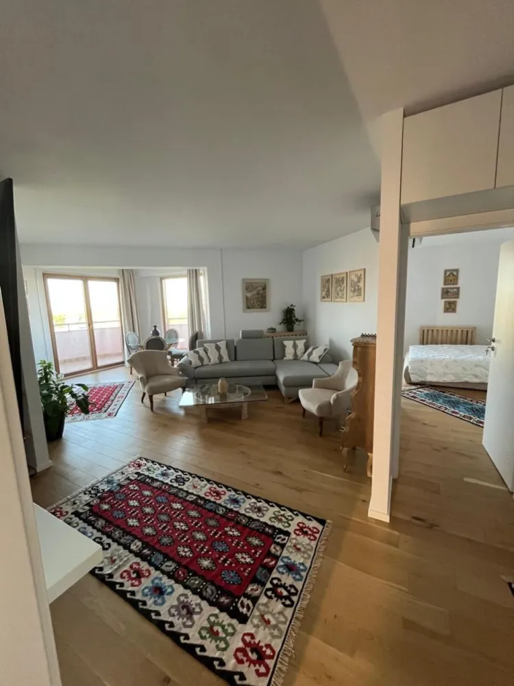 Piata Presei Libere apartament 3 camere de vanzare - K Imobiliare va propune in zona Piata Presei Libere apartament care arată foarte bine renovat, luminos și modern, cu un stil curat și aerisit. Se vede că a fost gândit pentru confort și estetică.

 Living
Spațios, open-space cu zona de dining
Multă lumină naturală datorită ferestrelor mari
Mobilier simplu, elegant
Bibliotecă încorporată + TV montat pe perete → aspect ordonat

Amplasată lângă balcon
Foarte luminoasă
Masă din sticlă + scaune elegante → senzație de spațiu
 Dormitoare
Luminoase, cu acces sau vedere spre exterior
Mobilate minimalist, dar plăcut
Un dormitor are birou (bun pentru work from home)
Aer condiționat instalat

 Băi
Design modern
Duș walk-in
Finisaje curate și actuale
Terasă & priveliște (mare plus)
Balcon curbat – element arhitectural rar
Priveliște deschisă spre oraș și spațiu verde
Etaj înalt → lumină + intimitate

 Compartimentare & suprafață
~92 mp utili + ~12 mp terasă = ~104 mp total
Compartimentare eficientă:
Separare bună zi/noapte
Spații de depozitare (hol + dressing)
🏢 Bloc & facilități
Construit în 2007
Dotări importante:
Sală fitness
Curățătorie
Restaurant
Pază 24/7
Lifturi Schindler

Foarte luminos
Terasă + vedere spectaculoasă
Complet mobilat (gata de mutare)
Renovare modernă
Facilități multiple în complex

Este un apartament foarte bun ca lifestyle, potrivit pentru:
cuplu sau familie mică
persoane care apreciază lumina naturală și view-ul
cineva care vrea să se mute fără renovări