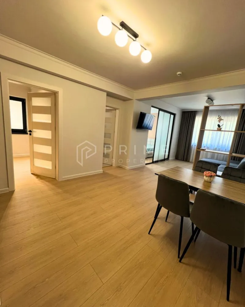 Apartament Premium 2 Camere | Zonă Semicentrală | Parcare - Amplasat într-o zonă semicentrală foarte bună, apartamentul oferă acces rapid către toate punctele de interes: magazine, farmacii, școli, grădinițe, parcuri și stații de transport în comun. Aveți tot ce vă trebuie la câteva minute distanță, fără a renunța la liniștea și confortul de acasă.

Compartimentare & Design Interior:
Interiorul impresionează printr-un design modern și armonios, în nuanțe neutre deschise, completate de textura caldă a lemnului și accente elegante de gri deschis. Materialele sunt de calitate superioară, iar mobilierul este nou, ales cu atenție pentru un ambient rafinat.

Livingul: Luminos, creează un spațiu aerisit și primitor.

Bucătăria: Separată, complet mobilată și utilată – perfectă pentru cei care preferă un spațiu distinct pentru gătit.
Dormitorul: Intim și relaxant, dotat cu pat matrimonial, noptiere moderne și aplice cu lumină ambientală pentru un plus de confort și stil.
Baia: Finisată cu foarte mult bun gust, dispune de plăci ceramice care imită lemnul în zona chiuvetei și a dușului, oferind un efect vizual cald și sofisticat.
Balcon: Atât livingul, cât și bucătăria au ieșire directă pe balcon.

Confort & Beneficii incluse:
Eficiență termică: Sistem de încălzire prin pardoseală, asigurând un confort uniform și costuri optimizate.
Dotări: Electrocasnice moderne și mobilier nou, de înaltă calitate.

Parcare securizată: Loc de parcare inclus în curtea interioară a imobilului, dotată cu poartă automatizată.

Condiții de închiriere:
Preț chirie: 550 Euro / lună.
Loc de parcare: inclus în preț.
Garanție: Contravaloarea a 2 luni de chirie.

Comision agenție: 50% din prima lună de chirie.

Un apartament ideal, cu acces facil către tot ce contează. Pentru detalii suplimentare și programarea unei vizionări, vă invităm să ne contactați!
