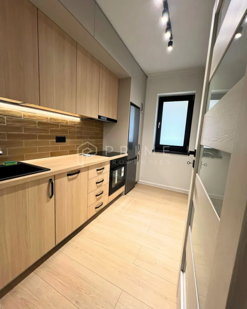 Apartament Premium 2 Camere | Zonă Semicentrală | Parcare - Amplasat într-o zonă semicentrală foarte bună, apartamentul oferă acces rapid către toate punctele de interes: magazine, farmacii, școli, grădinițe, parcuri și stații de transport în comun. Aveți tot ce vă trebuie la câteva minute distanță, fără a renunța la liniștea și confortul de acasă.

Compartimentare & Design Interior:
Interiorul impresionează printr-un design modern și armonios, în nuanțe neutre deschise, completate de textura caldă a lemnului și accente elegante de gri deschis. Materialele sunt de calitate superioară, iar mobilierul este nou, ales cu atenție pentru un ambient rafinat.

Livingul: Luminos, creează un spațiu aerisit și primitor.

Bucătăria: Separată, complet mobilată și utilată – perfectă pentru cei care preferă un spațiu distinct pentru gătit.
Dormitorul: Intim și relaxant, dotat cu pat matrimonial, noptiere moderne și aplice cu lumină ambientală pentru un plus de confort și stil.
Baia: Finisată cu foarte mult bun gust, dispune de plăci ceramice care imită lemnul în zona chiuvetei și a dușului, oferind un efect vizual cald și sofisticat.
Balcon: Atât livingul, cât și bucătăria au ieșire directă pe balcon.

Confort & Beneficii incluse:
Eficiență termică: Sistem de încălzire prin pardoseală, asigurând un confort uniform și costuri optimizate.
Dotări: Electrocasnice moderne și mobilier nou, de înaltă calitate.

Parcare securizată: Loc de parcare inclus în curtea interioară a imobilului, dotată cu poartă automatizată.

Condiții de închiriere:
Preț chirie: 550 Euro / lună.
Loc de parcare: inclus în preț.
Garanție: Contravaloarea a 2 luni de chirie.

Comision agenție: 50% din prima lună de chirie.

Un apartament ideal, cu acces facil către tot ce contează. Pentru detalii suplimentare și programarea unei vizionări, vă invităm să ne contactați!
