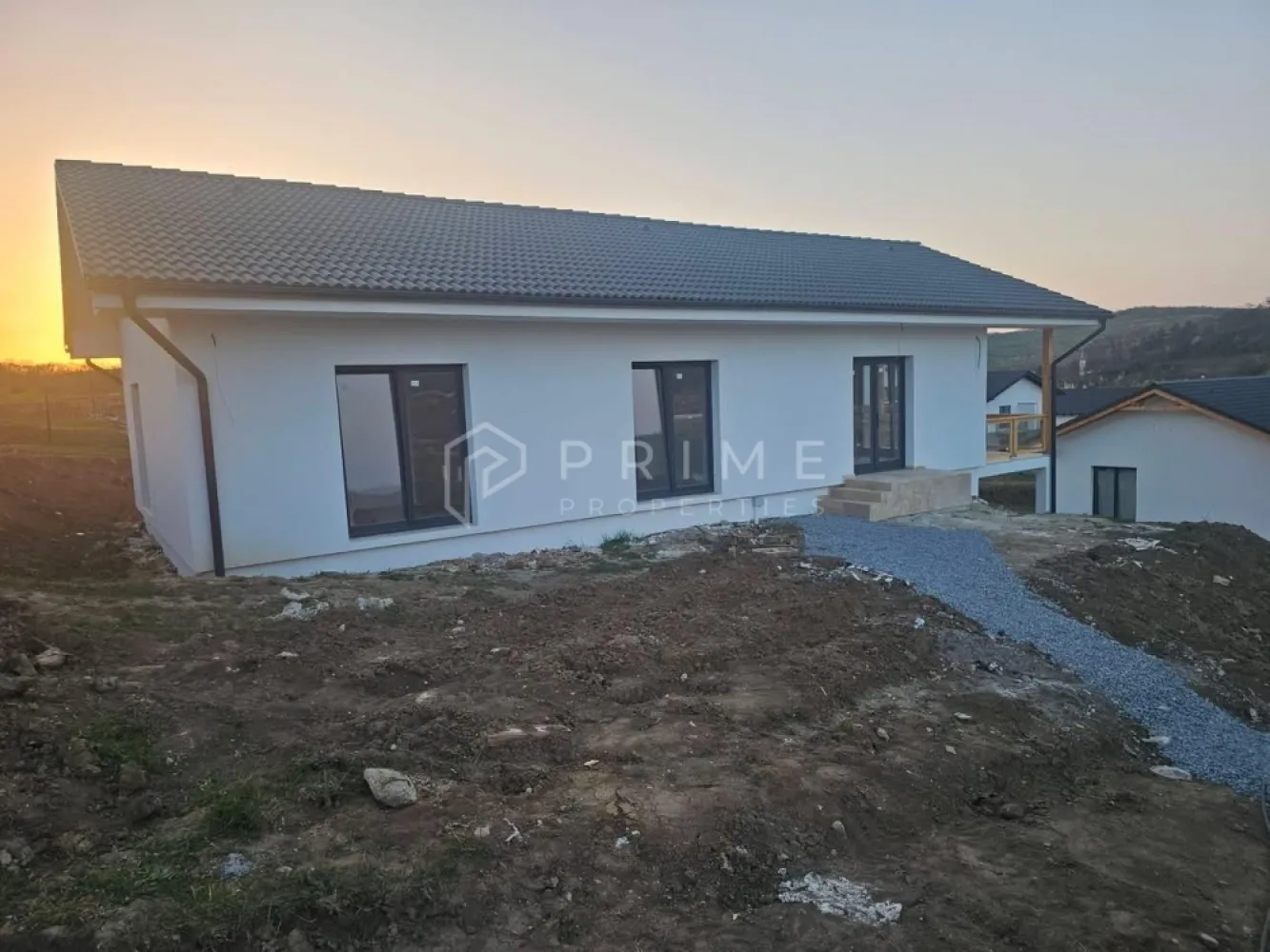 Vilă chalet modern cu perete panoramic de sticlă - Livezeni, Mureș - Vă prezentăm la vânzare o casă individuală cu design chalet contemporan, situată într-un cartier rezidențial aerisit din Livezeni, județul Mureș. Construcția impresionează prin peretele panoramic de sticlă pe toată înălțimea șarpantei, care inundă livingul cu lumină naturală și oferă o priveliște deschisă spre dealurile împrejmuitoare.
Planul interior se desfășoară pe un singur nivel, cu o configurație gândită pentru confort și funcționalitate: 
bucătărie cu living open-space, trei dormitoare generoase, două băi, dressing și cămară. 
Terasa acoperită de 25 m², cu balustradă din sticlă și lemn, prelungește natural spațiul de locuit spre exterior.
Podul este podit și poate fi utilizat ca spațiu de depozitare suplimentar, un avantaj rar în construcțiile noi.
Izolație superioară · eficiență energetică ridicată
Exterior termoizolat cu polistiren expandat de 15 cm; interior izolat cu spumă poliuretanică aplicată în strat continuu — eliminarea punților termice și consum redus de energie pe tot parcursul anului.
Proprietatea se vinde la stadiu semifinisat avansat. 

La Prime Properties, fiecare tranzacție înseamnă mai mult decât o simplă achiziție – este un proces complet, în care colaborăm cu cei mai buni profesioniști: notari, avocați, designeri, arhitecți, evaluatori, specialiști în certificate energetice, consultanți de credite imobiliare.
Astfel, atunci când alegi o proprietate prin noi, primești la pachet și siguranță, transparență și servicii impecabile pe tot parcursul drumului tău către casa ideală.
Ne dedicăm 100% fiecărui client, iar asta se reflectă în rezultate și în încrederea pe care o primim înapoi prin recomandările lor.
Proprietatea aceasta nu se potrivește exact nevoilor tale?
Lasă-ne să îți găsim alternativa potrivită. Agentul nostru îți va oferi soluții avantajoase și adaptate stilului tău de viață.
📞 Contactează-ne astăzi. Până acum nu am dezamăgit niciun client – și nu vom începe cu tine.
Comision 0% pentru cumpărători