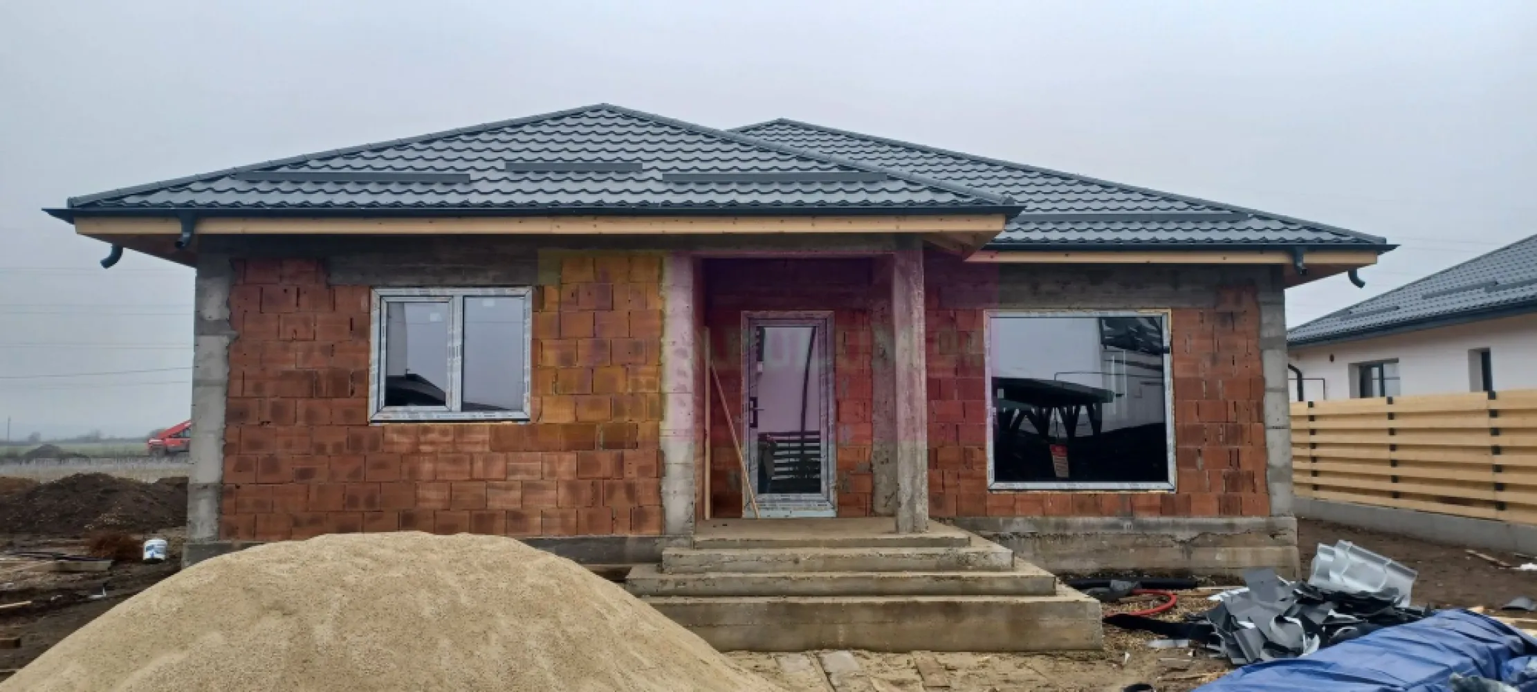 Săbăreni, casă nouă 4 camere parter, curte 480 mp - Casa se află în Săbăreni, într-o zonă rezidențială nouă, ferită de traficul rutier, în vecinătatea celor 2 păduri. Este un imobil tip parter, cu structura de rezistență din beton armat și zidărie din căramidă, fără pereți din rigips. Este acoperită cu țiglă metalică mată iar tâmplăria este Salamander cu geamuri tripan. Casa se izolează termic la exterior cu polistiren de 150 mm peste care se aplică tencuială decorativă siliconată. Imobilul are placă din beton armat peste parter, podul este înalt și izolat termic cu celuloză. Locuința beneficiază de încălzire în pardoseală și centrală termică pe gaze, în condensație. Finisajele interioare (parchet, gresie, faință, usi, obiecte sanitare) pot fi alese de cumpărător, într-un anumit buget. Casa are 3 dormitoare, living, bucătărie (închisă), 2 băi, dresing, hol, cameră tehnică, pivniță si terasă acoperită. Curte 480 mp, împrejmuită. Termen de finalizare, la cheie, 3 luni. Pret 145.000 EUR. Nu se plătește TVA sau comision