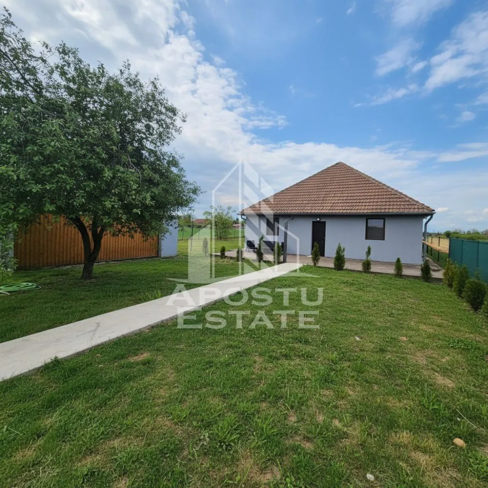 Casă 133 mp utili, teren 2972 mp, la 30 min de Timișoara - Apostu Estate vă prezintă spre vânzare o casă situată în Sânpetru Mic, amplasată pe un teren generos de 2.972 mp, cu o suprafață utilă de 133 mp. Proprietatea este ideală pentru o familie care își dorește liniște, spațiu verde și confort, oferind atât o locuință bine compartimentată, cât și un teren mare cu multiple posibilități de amenajare.
Casa este compusă din 5 camere, dintre care 4 dormitoare, un living spațios cu bucătărie open-space complet mobilată și utilată, 1 baie cu duș și hol de acces. Imobilul a fost construit în anul 2010 și beneficiază de o structură modernă, cu ferestre termopan, uși PVC și izolație exterioară de 5 cm.
Confortul termic este asigurat de o centrală pe lemne, completată de un boiler electric de 75 litri, iar instalația de încălzire este realizată cu radiatoare și țeavă de cupru. Pardoseala este finisată cu parchet în living și în dormitoare, iar în hol și bucătărie au fost montate gresie și faianță, pentru un plus de funcționalitate și întreținere ușoară.
Proprietatea dispune de internet, alimentare cu apă de la rețea și electricitate monofazică. Gazul se află la poarta de intrare și urmează să fie introdus în casă, ceea ce reprezintă un avantaj important pentru viitorul proprietar.
În curte există un garaj acoperit, cu loc pentru două mașini, iar terenul include și o grădină foarte generoasă, ideală pentru relaxare, agricultură de familie sau amenajări suplimentare. O proprietate potrivită pentru cei care caută o casă primitoare, funcțională și cu un potențial excelent.