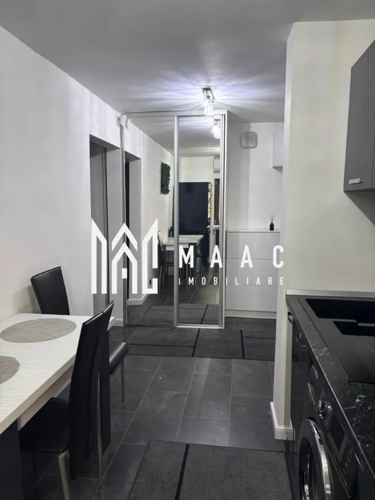 Apartament 2 camere | Nord | Etaj 1 | 44 mpu | - MAAC Imobiliare vă propune spre vânzare un apartament modern și elegant, amenajat într-un stil ultra-modern, cu finisaje premium și atenție deosebită la fiecare detaliu. Proprietatea impresionează prin designul contemporan, paleta cromatică rafinată și compartimentarea practică, fiind ideală pentru un cuplu, o persoană activă sau pentru investiție în vederea închirierii.
Locuința este pregătită pentru mutare imediată și oferă un ambient exclusivist, unde confortul și estetica se îmbină perfect.
Caracteristici:
Apartament modern și complet utilat
Design interior ultra-modern
Finisaje premium
Compartimentare practică și eficientă
Ideal pentru locuit sau investiție
Mutare imediată
Compartimentare:
Living spațios și luminos
Dormitor matrimonial elegant
Bucătărie complet mobilată și utilată
Baie modernă
Hol funcțional cu spații de depozitare
Living:
Canapea generoasă de tip colțar
Perete decorativ cu finisaj special și reflexii sidefate
Mobilier minimalist negru lucios
Corpuri de iluminat cu design geometric futurist
Draperii elegante pentru intimitate și confort
Atmosferă modernă și rafinată
Dormitor:
Pat matrimonial cu tapițerie neagră
Perete decorativ texturat
Dressing integrat
Iluminat ambiental modern
Spațiu confortabil și relaxant
Bucătărie:
Mobilier custom-made negru lucios
Blat cu aspect de marmură neagră
Plită incorporată
Cuptor electric
Hotă
Cuptor cu microunde
Mașină de spălat rufe integrată
Zonă de dining elegantă
Masă albă și scaune din piele ecologică
Baie:
Cadă cu hidromasaj tip jacuzzi
Finisaje ceramice moderne
Calorifer portprosop negru mat
Mobilier funcțional și elegant
Dotări și finisaje:
Aer condiționat modern
Gresie porțelanată în nuanțe închise
Uși interioare moderne cu inserții din aluminiu
Ferestre termopan de calitate superioară
Corpuri de iluminat premium
Elemente decorative moderne
Tablou decorativ cu mușchi stabilizați
Avantaje:
Design exclusivist și modern
Finisaje premium și materiale de calitate
Spații optimizate eficient
Ideal pentru mutare imediată
Perfect pentru investiție și închiriere premium
Confort ridicat și atmosferă elegantă
Pentru mai multe informații și programarea unei vizionări, echipa MAAC Imobiliare vă stă la dispoziție. ID 3109493