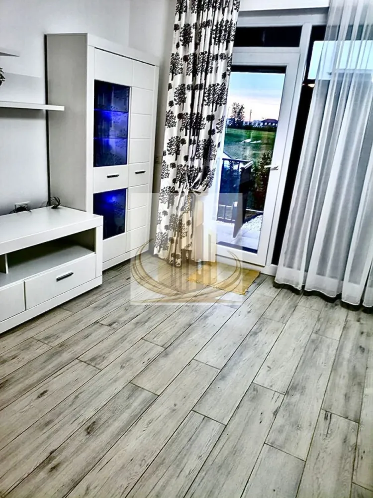 Ap cu 2 cam și curte proprie de 115 mp, Giroc | Bloc nou | Investitie - Echipa Grand Mobilis Imobiliare vă propune spre vânzare o proprietate cu adevărat specială, un apartament care reușește să combine perfect confortul unui apartament modern cu intimitatea și atmosfera unei case, datorită curții proprii generoase și amenajării atent gândite.

Situat la parterul unui imobil nou construit în anul 2022, apartamentul impresionează prin designul contemporan, finisajele premium și atenția la detalii, fiecare spațiu fiind amenajat cu materiale de calitate și mult bun gust.

Locuința este decomandată și beneficiază de o compartimentare extrem de practică și echilibrată:

hol generos de acces;
living luminos și primitor;
bucătărie închisă, separată;
dormitor spațios;
baie modern amenajată.

Încă de la intrare, apartamentul transmite senzația unui spațiu elegant, cald și aerisit, ideal pentru cei care își doresc un cămin modern, gata de mutare imediată. Proprietatea se vinde complet mobilată și utilată, exact cum se prezintă.

Confortul termic este asigurat prin intermediul centralei proprii și al încălzirii în pardoseală, oferind un plus de confort și eficiență energetică.

Elementul care transformă această proprietate într-una rară pe piață este curtea proprie de aproximativ 115 mp, amenajată cu atenție pentru a crea un adevărat spațiu de relaxare privat. Curtea este frumos întreținută și dispune de:

gazon;
plante ornamentale;
pietriș decorativ;
pavaj;
zone ideale pentru relaxare și petrecerea timpului în aer liber.

În plus, în curte regăsim și o căsuță cu utilități trase, perfectă pentru depozitare, hobby sau amenajarea unui spațiu suplimentar multifuncțional.

Proprietatea beneficiază și de 2 locuri de parcare înscrise în CF, un avantaj extrem de important pentru confortul cotidian.

Un alt aspect rar întâlnit este faptul că accesul în apartament se poate face atât prin interiorul blocului, cât și direct din curtea proprie, oferind intimitate și senzația autentică de locuință tip casă.

Poziționarea completează perfect această proprietate:

zonă liniștită și aerisită;
magazine, restaurante și cafenele în apropiere;
școală, grădiniță, creșă și liceu;
mijloace de transport în comun;
acces rapid către principalele artere ale orașului;
centura ocolitoare la aproximativ 10-12 minute distanță.

Acest apartament este alegerea ideală pentru o familie sau un cuplu care își dorește mai mult decât o simplă locuință — un spațiu modern, elegant și intim, unde confortul interior se îmbină perfect cu avantajele unei curți generoase.

Totodată, proprietatea reprezintă și o oportunitate excelentă de investiție, datorită cererii ridicate pentru închiriere în zonă și a caracteristicilor rare pe care le oferă. 

Pentru mai multe detali sau programarea unei vizionari, echipa Grand Mobilis Imobiliare va sta la dispozitie! 
ID Intern: CP3106818