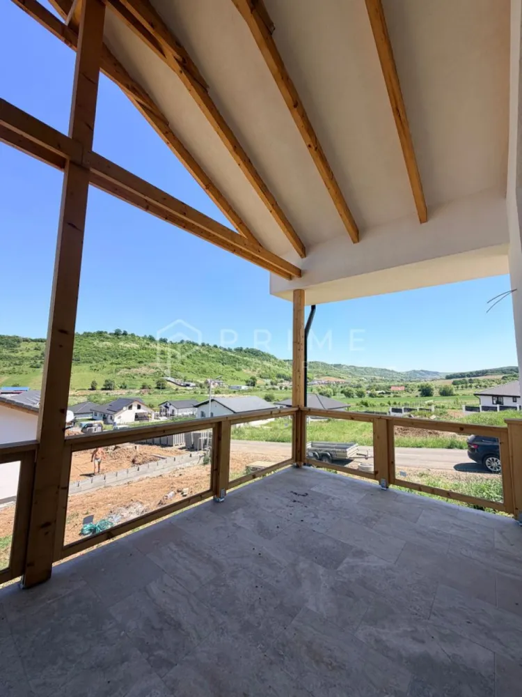 Vilă chalet modern cu perete panoramic de sticlă - Livezeni, Mureș - Vă prezentăm la vânzare o casă individuală cu design chalet contemporan, situată într-un cartier rezidențial aerisit din Livezeni, județul Mureș. Construcția impresionează prin peretele panoramic de sticlă pe toată înălțimea șarpantei, care inundă livingul cu lumină naturală și oferă o priveliște deschisă spre dealurile împrejmuitoare.
Planul interior se desfășoară pe un singur nivel, cu o configurație gândită pentru confort și funcționalitate: 
bucătărie cu living open-space, trei dormitoare generoase, două băi, dressing și cămară. 
Terasa acoperită de 25 m², cu balustradă din sticlă și lemn, prelungește natural spațiul de locuit spre exterior.
Podul este podit și poate fi utilizat ca spațiu de depozitare suplimentar, un avantaj rar în construcțiile noi.
Izolație superioară · eficiență energetică ridicată
Exterior termoizolat cu polistiren expandat de 15 cm; interior izolat cu spumă poliuretanică aplicată în strat continuu — eliminarea punților termice și consum redus de energie pe tot parcursul anului.
Proprietatea se vinde la stadiu finisat.

La Prime Properties, fiecare tranzacție înseamnă mai mult decât o simplă achiziție. Este un proces complet, în care colaborăm cu cei mai buni profesioniști: notari, avocați, designeri, arhitecți, evaluatori, specialiști în certificate energetice, consultanți de credite imobiliare.
Astfel, atunci când alegi o proprietate prin noi, primești la pachet și siguranță, transparență și servicii impecabile pe tot parcursul drumului tău către casa ideală.
Ne dedicăm 100% fiecărui client, iar asta se reflectă în rezultate și în încrederea pe care o primim înapoi prin recomandările lor.
Proprietatea aceasta nu se potrivește exact nevoilor tale?
Lasă-ne să îți găsim alternativa potrivită. Agentul nostru îți va oferi soluții avantajoase și adaptate stilului tău de viață.
📞 Contactează-ne astăzi. Până acum nu am dezamăgit niciun client și nu vom începe cu tine.
Comision 0% pentru cumpărători
