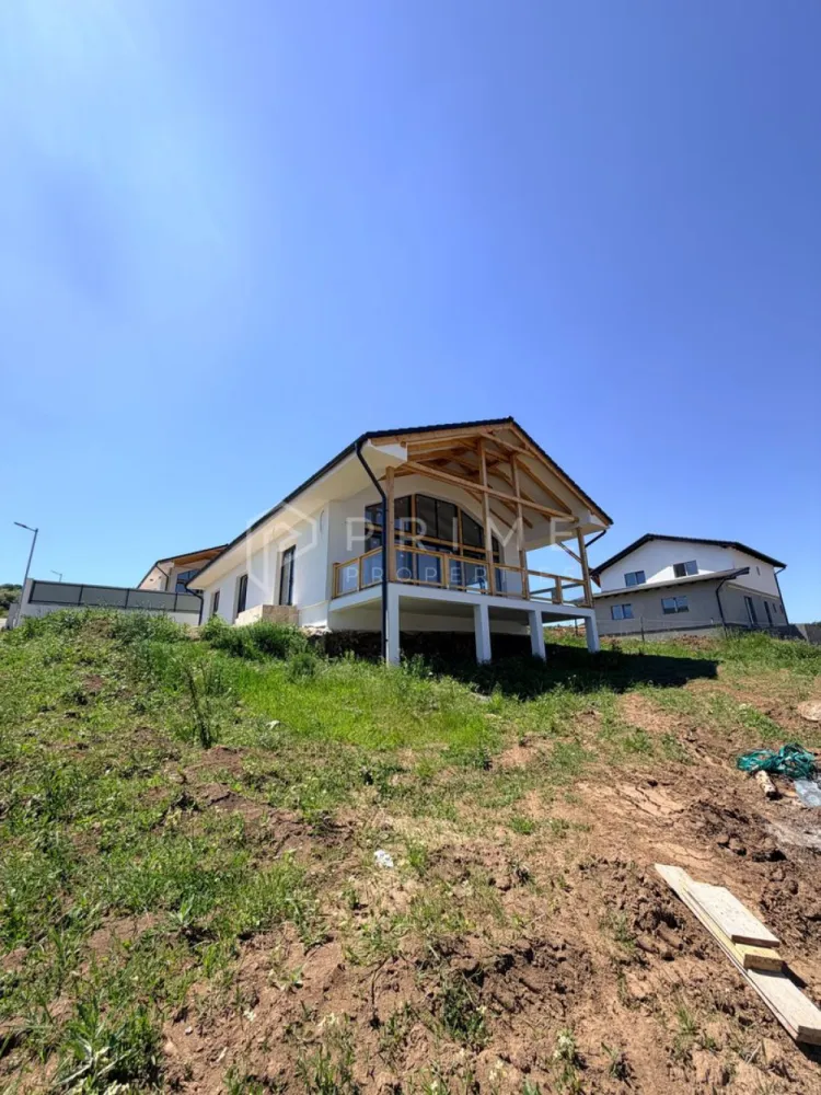 Vilă chalet modern cu perete panoramic de sticlă - Livezeni, Mureș - Vă prezentăm la vânzare o casă individuală cu design chalet contemporan, situată într-un cartier rezidențial aerisit din Livezeni, județul Mureș. Construcția impresionează prin peretele panoramic de sticlă pe toată înălțimea șarpantei, care inundă livingul cu lumină naturală și oferă o priveliște deschisă spre dealurile împrejmuitoare.
Planul interior se desfășoară pe un singur nivel, cu o configurație gândită pentru confort și funcționalitate: 
bucătărie cu living open-space, trei dormitoare generoase, două băi, dressing și cămară. 
Terasa acoperită de 25 m², cu balustradă din sticlă și lemn, prelungește natural spațiul de locuit spre exterior.
Podul este podit și poate fi utilizat ca spațiu de depozitare suplimentar, un avantaj rar în construcțiile noi.
Izolație superioară · eficiență energetică ridicată
Exterior termoizolat cu polistiren expandat de 15 cm; interior izolat cu spumă poliuretanică aplicată în strat continuu — eliminarea punților termice și consum redus de energie pe tot parcursul anului.
Proprietatea se vinde la stadiu finisat.

La Prime Properties, fiecare tranzacție înseamnă mai mult decât o simplă achiziție. Este un proces complet, în care colaborăm cu cei mai buni profesioniști: notari, avocați, designeri, arhitecți, evaluatori, specialiști în certificate energetice, consultanți de credite imobiliare.
Astfel, atunci când alegi o proprietate prin noi, primești la pachet și siguranță, transparență și servicii impecabile pe tot parcursul drumului tău către casa ideală.
Ne dedicăm 100% fiecărui client, iar asta se reflectă în rezultate și în încrederea pe care o primim înapoi prin recomandările lor.
Proprietatea aceasta nu se potrivește exact nevoilor tale?
Lasă-ne să îți găsim alternativa potrivită. Agentul nostru îți va oferi soluții avantajoase și adaptate stilului tău de viață.
📞 Contactează-ne astăzi. Până acum nu am dezamăgit niciun client și nu vom începe cu tine.
Comision 0% pentru cumpărători