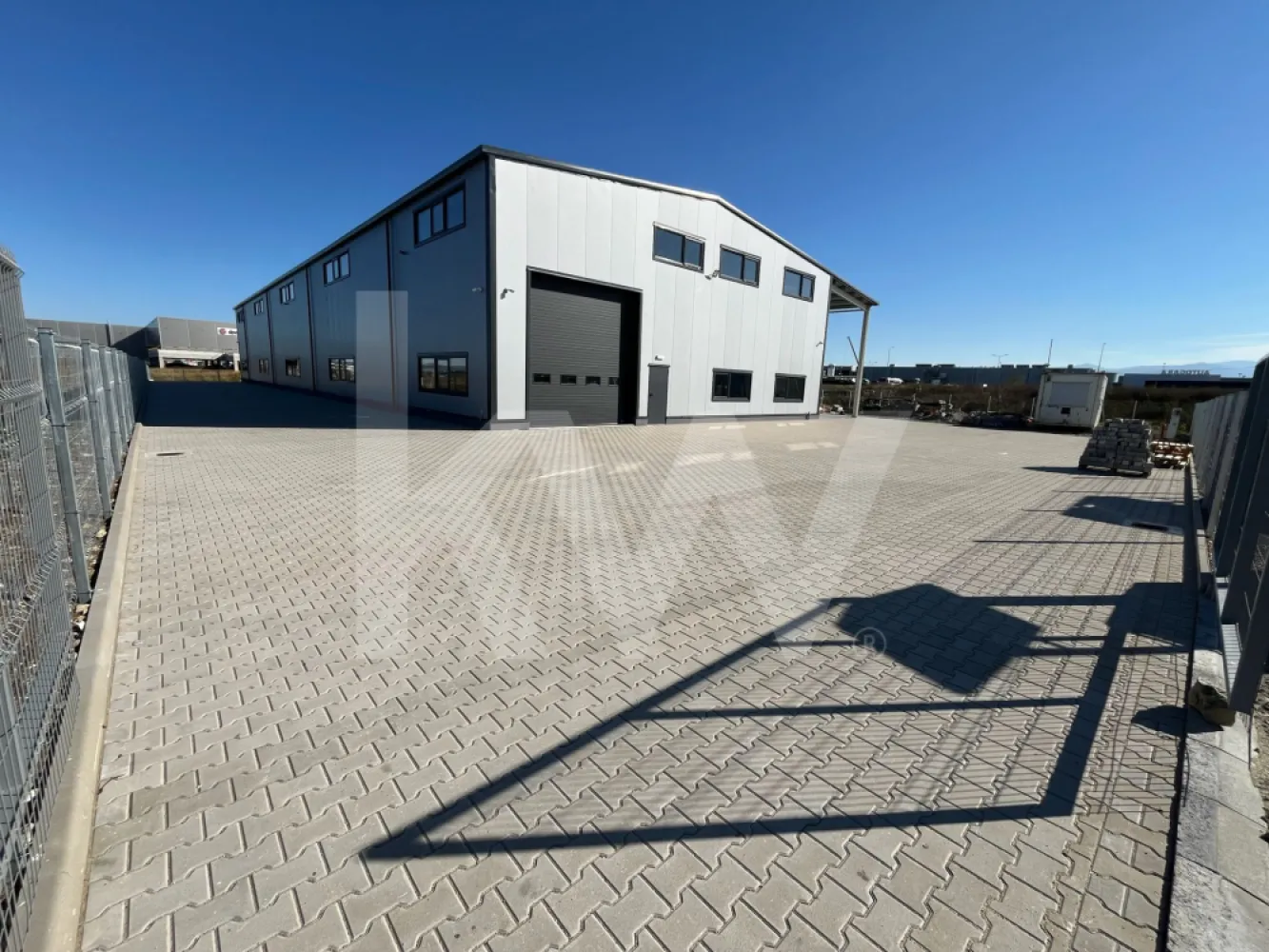 DE ÎNCHIRIAT — Hală producție/depozitare + birouri. Parcul Industrial Vest-Sibiu - DE ÎNCHIRIAT — Hală producție/depozitare + birouri | Parcul Industrial Vest, Sibiu | 2026

O hală nouă arată diferit. Aceasta chiar arată diferit.

Dacă ai văzut destule hale cu pereți mucegăiți, pardoseli crăpate și birouri improvizate dintr-un container, oprește-te aici. Această proprietate a fost construită în 2026, la un standard pe care îl vei vedea imediat la prima vizionare — și pe care îl vei simți în costurile de operare în fiecare lună.

LOCAȚIE
Parcul Industrial Vest, Sibiu
2 km față de centura orașului | 5 min de aeroport | Fără restricții de tonaj | Acces direct TIR 

CE ÎNCHIRIEZI
HALA — ~960 mp utili  (două nave comunicante: ~535 + ~425 mp)
- Înălțime liberă utilă minimă: 6,10 m | Înălțime la coamă: 8,4 m
- Structură cadre metalice, pereți panouri sandwich 100 mm (REI 15)
- Pardoseală beton elicopterizat cu inserție quartz — standard DIN 18202
- 2 uși drive-in electrice L 4,2 ml × H 4,5 ml + ușă de comunicare între nave (3,5 × 3,5 m)
- Iluminat LED high-bay
- Încălzire prin tuburi radiante pe gaz — sistem eficient energetic pentru volume mari
- Sistem automat de desfumare prin ferestre acționate mecanic
- Hidranți interiori și exteriori

BIROURI — ~360 mp (parter + etaj parțial)
- Finisaje complete: SPC tarkett și gresie, vopsea lavabilă
- Încălzire în pardoseală + centrale pe gaz cu puffere TESY (sistem dublu, independent pentru fiecare aripă)
- Aer condiționat split în toate birourile
- Grupuri sanitare separate femei/bărbați — finisate cu plăci mari format marmură
- Sală de mese/bucătărie echipată (mobilier inclus)
- Vestiare separate femei/bărbați
- Cameră tehnică dedicată

EXTERIOR
- Platformă exterior totală: ~2.600 mp — pavaj + asfalt frezat copactat rezistent la trafic TIR
- Acces circular TIR în jurul clădirii
- 10 locuri de parcare
- Împrejmuire perimetrală metalică H=2 m | CCTV
- Copertină de acces la intrarile principale

UTILITĂȚI
- Energie electrică: 200 kW putere aprobată | Trafo propriu 250 kVA | Subcontorizare separată pe cele două corpuri
- Gaze naturale: racordate, contorizare separată (1 contor principal + 4 subcontoare)
- Apă: rețea municipală
- Canalizare: fosă septică industrială proprie + separator de hidrocarburi
- Internet fibră optică: în curs de racordare (negocieri în desfășurare cu operatorul)

 SITUAȚIE JURIDICĂ
- Autorizație ISU: în curs de finalizare

CONDIȚII COMERCIALE
- Chirie: 8.900 EUR/lună + TVA (hală + birouri, pachet complet)
- Contract minim: 3 ani
- Garanție: echivalent 2 luni chirie
- Posibilitate personalizare spațiu (fit-out) — se discută de la caz la caz
- Nu se închiriază separat hala de birouri

 POTRIVIT PENTRU
Producție ușoară și medie | Asamblare | Logistică și distribuție | Service tehnic | Depozitare

*Nu se acceptă: reciclare deșeuri, colectare fier vechi, procesare chimică grea.

Vizionare: disponibilă imediat, cu programare.
Contact: Caius Giurgiu | [0790823369]
