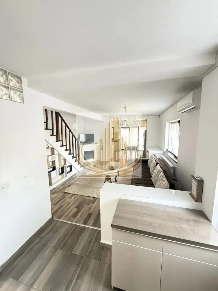 Casă Modernă cu 4 Cam, 2 bai | Dumbravita | Zona Padure | - Echipa Grand Mobilis Imobiliare vă propune spre vânzare o proprietate deosebită, situată într-una dintre cele mai apreciate zone rezidențiale din Dumbrăvița, ideală pentru familiile care își doresc confort, intimitate și acces rapid către toate facilitățile importante ale orașului.

Cu o suprafață utilă de aproximativ 100 mp și un teren de 280 mp, această locuință se remarcă prin compartimentarea eficientă, spațiile luminoase și atmosfera primitoare. Proprietatea este ultima unitate din cadrul ansamblului de case înșiruite, beneficiind astfel de un teren mai generos și de un plus de intimitate față de majoritatea proprietăților similare din zonă.

Compartimentarea este ideală pentru o familie:

hol de acces;
living spațios cu bucătărie open-space și ieșire directă către terasă;
3 dormitoare (unul putând fi utilizat ca birou sau cameră pentru copii);
2 băi;
dressing;
pod izolat, ideal pentru depozitare.

Casa se vinde mobilată și utilată în proporție de aproximativ 90%, fiind pregătită pentru mutare imediată. De altfel, proprietatea beneficiază de multiple dotări care contribuie la confortul zilnic:

centrală termică proprie pe gaz, schimbată în anul 2025;
încălzire prin calorifere;
aer condiționat la parter și etaj;
poartă automatizată cu control de pe telefon;
sistem de alarmă;
sistem de supraveghere video;
sistem automat de irigații;
acces auto pavat.

Unul dintre marile avantaje ale proprietății îl reprezintă spațiul exterior. Curtea este amenajată cu mult bun gust și atenție la detalii, fiind un loc perfect pentru relaxare. Regăsim aici gazon atent întreținut, plante ornamentale, zone decorative cu pietriș alb și un sistem automatizat de irigații care menține grădina într-o stare impecabilă pe tot parcursul anului.

În partea din spate a proprietății se află o anexă din lemn, ideală pentru depozitare, precum și o zonă special amenajată pentru câini, un detaliu apreciat de familiile care dețin animale de companie.

Poziționarea reprezintă un alt punct forte al proprietății. Casa este amplasată într-o zonă foarte liniștită, predominant rezidențială, însă beneficiază de acces rapid către toate facilitățile necesare unui stil de viață modern. În imediata apropiere regăsim școală, grădiniță, after-school, magazine și supermarketuri (Kaufland, Mega Image, Profi), restaurante, cafenele, piață, teren de fotbal și mijloace de transport în comun.
Totodată, proprietatea se află la doar câteva minute de mers pe jos de parc și pădure, fiind alegerea ideală pentru persoanele care apreciază plimbările în natură și activitățile în aer liber. În același timp, accesul către principalele artere și către punctele de interes ale orașului este rapid și facil.

Prin combinația dintre locația excelentă, terenul generos, curtea superb amenajată și dotările moderne, această proprietate reprezintă alegerea ideală pentru o familie care își dorește un cămin complet, într-o zonă liniștită și foarte bine conectată.

Pentru mai multe detalii, ne puteti suna!
CP3177049