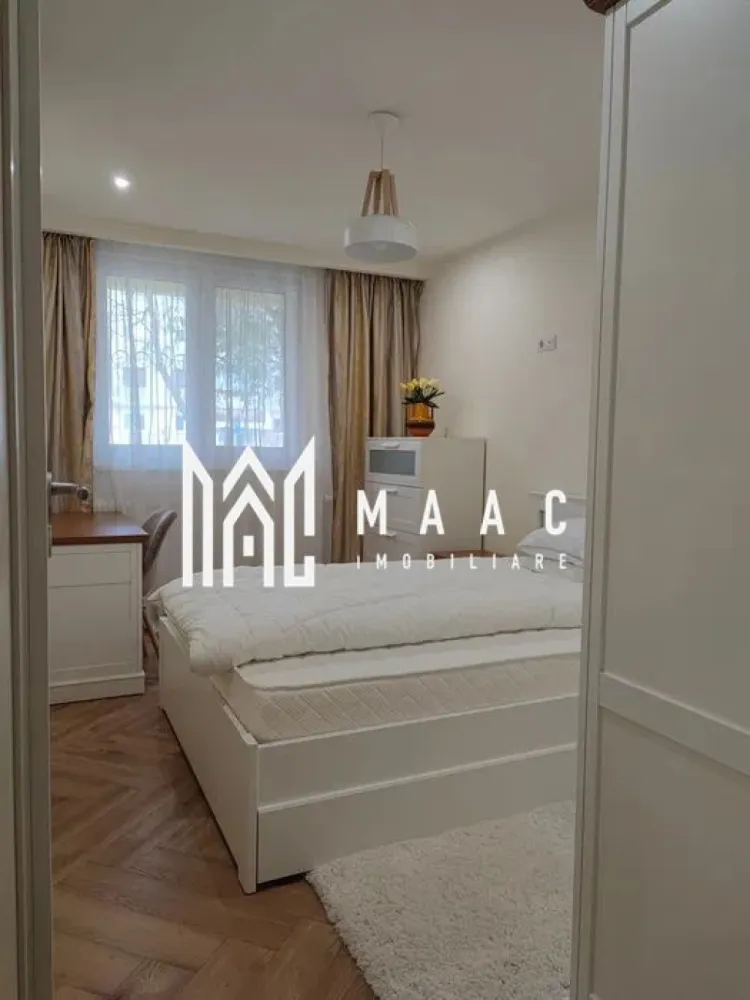 Apartament | 2 camere | Parter | Spatiu verde | Strand - Maac Imobiliare vă propune spre închiriere un apartament cu 2 camere decomandate, situat într-una dintre cele mai apreciate zone ale Sibiului – cartierul Ștrand, zona vilelor, într-un cadru verde și liniștit, aproape de Parcul Sub Arini și Centrul orașului. Apartamentul este amplasat la parter, are o suprafață utilă de 50 mp și este compartimentat eficient, fiind format din hol de acces, living luminos, dormitor, bucătărie separată și baie cu geam. Imobilul este construit din cărămidă și beneficiază de izolație termică, oferind un confort sporit pe tot parcursul anului. Un avantaj important îl reprezintă intimitatea, apartamentul având un singur perete comun cu vecinii, respectiv cel aferent bucătăriei. Locuința este mobilată complet, cu mobilier masiv din lemn natural, atent ales pentru durabilitate și eleganță. Dormitorul este dotat cu saltea cu suport ortopedic, cu multiple caracteristici pentru un somn odihnitor, iar pentru confort termic este asigurată o pilotă cu umplutură din puf și pene de gâscă, ideală pentru sezonul rece (pentru vară se poate discuta achiziționarea unei pilote adaptate preferințelor chiriașului). Apartamentul este complet utilat, punând la dispoziție toate electrocasnicele necesare, inclusiv mașină de spălat vase și uscător de rufe. În imediata apropiere se află o sală de sport, la doar 2 minute de mers pe jos. Se pretează unei persoane sau unui cuplu care își dorește liniște, confort și acces rapid către zonele centrale ale orașului. Condiții de închiriere: Se percepe o garanție în cuantumul unei chirii lunare. Nu se acceptă animale de companie. Pentru mai multe detalii și programarea unei vizionări, vă invităm să contactați Maac Imobiliar, specificând ID: CP2856246 }}