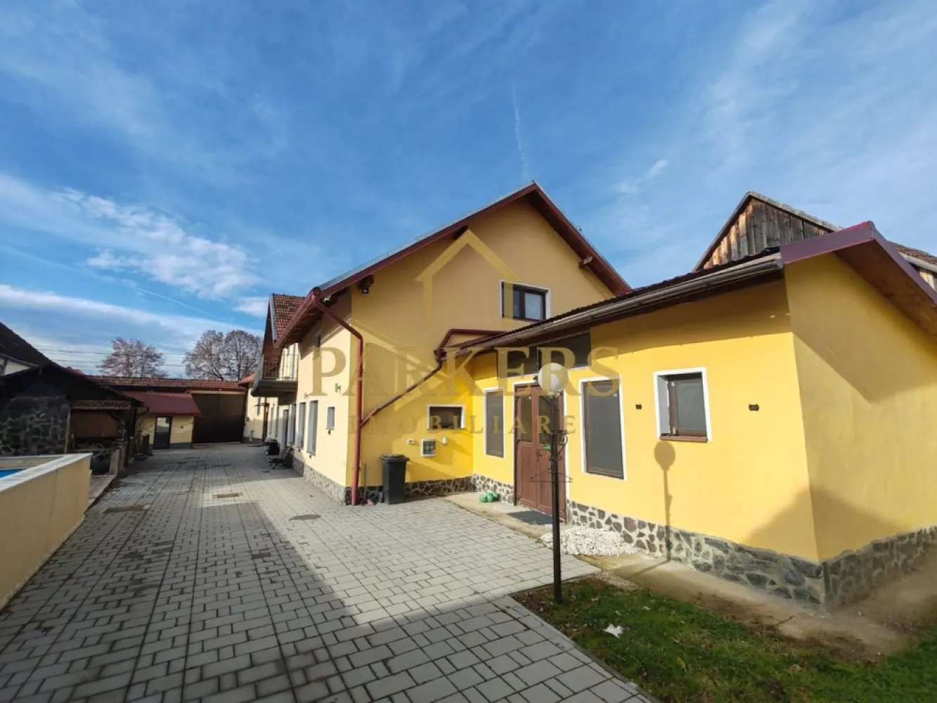 Reședință exclusivistă – 600 mp utili, facilități complete - Proprietate de excepție – eleganță, spațiu și funcționalitate la standarde înalte Parkers Imobiliare vă propune spre vânzare o reședință impresionantă, concepută pentru confort, intimitate și un stil de viață complet, situată într-un cadru sigur și bine organizat. Imobilul este dispus pe două niveluri, cu pivniță interioară, oferind o suprafață generoasă de aproximativ 600 mp utili, excelent compartimentați. Zona de acces întâmpină printr-un spațiu de tip vestiar, cu intrare către pivniță și camera tehnică, echipată cu două sisteme de încălzire: centrală pe gaz de 35 kW și centrală pe lemne de 80 kW – o soluție eficientă și sigură pentru orice sezon. Parterul este dedicat vieții de zi, cu un living amplu, luminos, care face legătura naturală între zonele funcționale ale casei. Bucătăria este complet utilată și dotată cu cuptor pe lemne, având acces către cămara și spălătorie, iar spațiul este completat de băi și zone de depozitare bine gândite. Tot la acest nivel se află și zona de noapte, compusă din holuri, două dormitoare și baie, oferind intimitate și confort. Etajul adaugă valoare printr-o compartimentare practică și versatilă: dormitoare spațioase, birou, dressing / depozit pentru haine și accesorii, baie, spații de depozitare și un balcon comunicant, ideal pentru momente de relaxare. Proprietatea se vinde complet mobilată și utilată, cu mobilier și accesorii atent alese, gata pentru mutare imediată. Exteriorul completează perfect experiența acestei reședințe: curte amenajată și împrejmuită garaj cu grup sanitar propriu foisor cu apă terasă generoasă piscină sală de fitness șemineu și zonă de grătar grădină bine întreținută proprietate sigură și privată Această casă nu este doar un imobil, ci un concept de locuire premium, ideal pentru o familie care își dorește spațiu, confort și independență, fără compromisuri. }}