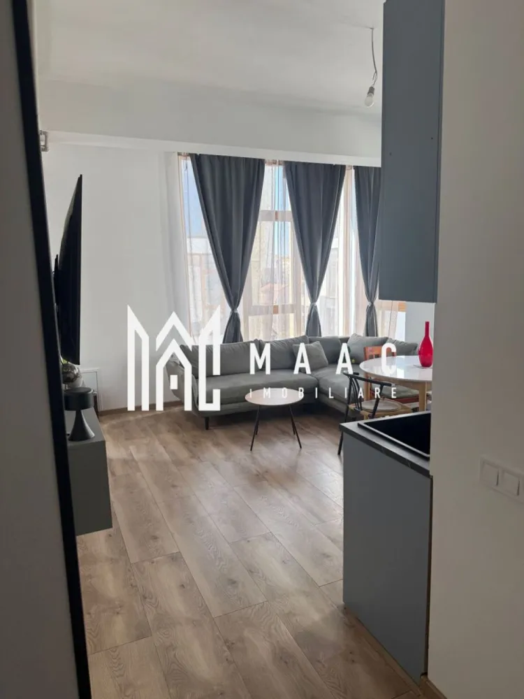 Apartament 3 Camere I Etaj 1 I 63 MPU I Terasa I O. Goga - MAAC Imobiliare vă propune spre vânzare un apartament modern cu 3 camere, decomandat, luminos și foarte bine compartimentat, situat într-o zonă excelentă – vis-a-vis de Shopping City Sibiu. Locuința impresionează prin spațiul generos, tavanele înalte și finisajele premium, fiind alegerea ideală pentru cei care își doresc confort, design modern și acces rapid la toate facilitățile orașului.Se vinde complet mobilat și utilat, fiind practic gata pentru mutare. Proprietatea a fost locuită doar ocazional, motiv pentru care se prezintă aproape ca nouă, necesitând doar câteva mici retușuri pentru finalizare. Compartimentare: living spațios cu bucătărie open-space două dormitoare confortabile baie modernă terasă balcon Dotări și finisaje premium: ✔ încălzire în pardoseală pentru confort termic superior ✔ centrală termică în condensare, foarte economică, cu termostate automatizate pentru fiecare încăpere ✔ aer condiționat cu funcție de răcire și încălzire ✔ uși înalte, de calitate germană, cu izolare fonică ridicată ✔ parchet rezistent la apă, compatibil cu încălzirea în pardoseală, cu folie izolatoare premium (transfer termic excelent) ✔ bucătărie realizată la comandă, complet echipată: frigider, mașină de spălat vase, cuptor încorporat, plită electrică + gaz și espressor ✔ masă extensibilă robustă pentru până la 10 persoane, cu scaune moderne ✔ canapea designer, de calitate superioară ✔ paturi de 180 cm cu saltele premium ✔ șifoniere moderne, înalte și încăpătoare ✔ mașină de spălat rufe cu uscător ✔ duș walk-in la nivelul pardoselii, realizat pe comandă din sticlă cu strat antibacterian ✔ blat de marmură pentru baie, adus din Italia și finisat la comandă ✔ Smart TV 65” 4K, 144Hz Loc de parcare. Apartamentul este situat într-un cartier modern, în plină dezvoltare, cu grad de ocupare în continuă creștere și acces rapid către magazine, restaurante, transport și zone comerciale, toate la câteva minute de mers pe jos. Pentru mai multe detalii si programarea unei vizionari vă rugăm să specificați că ați văzut anunțul cu ID: CP2969270. }}