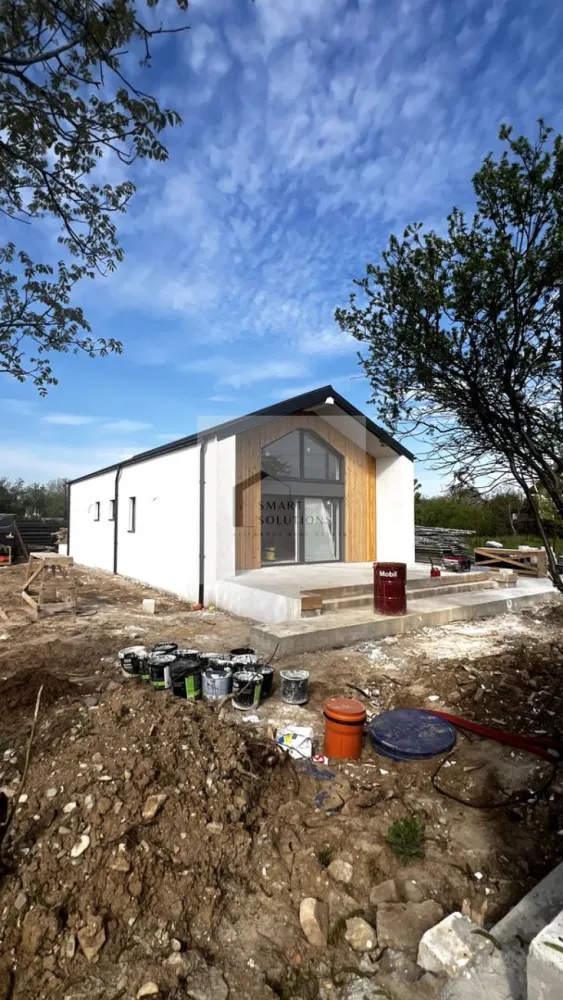 Casă Individuală Premium pe Parter | Eficiență Energetica Maxima - Vă propunem spre vânzare o locuință modernă, proiectată exclusiv pe parter, care îmbină designul minimalist cu funcționalitatea supremă. Situată într-o zonă liniștită din Clinceni, casa este refugiul ideal pentru cei care vor să evadeze din agitația urbană, fără a sacrifica accesul rapid către București. Preț: 155.000 EUR (Proiect "La Gata" – finisaje incluse) - COMISION 0% Teren Generos: Beneficiați de un lot de 490 mp, oferind o curte spațioasă, asigurând intimitate și spațiu pentru relaxare. Arhitectură de Excepție: Living de tip open space cu tavan înalt, care oferă o senzație de volum și libertate, rar întâlnită în segmentul rezidențial. Conexiune cu Natura: Fiecare cameră dispune de ieșire directă pe terase, eliminând bariera dintre interior și exterior și inundând spațiul cu lumină naturală prin suprafețele vitrate mari. Eficiență Energetică : Dotată cu pompă de căldură și infrastructură completă pentru panouri fotovoltaice. Aceste sisteme pot reduce costurile cu energia pentru încălzire și apă caldă cu până la 85%. Compartimentare și Specificații: Suprafață Utilă: 114 mp optimizați inteligent. Camere: 3 dormitoare luminoase și un living generos cu zonă de dining. Băi: 2 băi cu design modern. Utilități Complete: Apă curentă, canalizare, și curent electric. Parcare: Spațiu amenajat pentru minimum 2 autoturisme. Dotări Premium incluse în preț: Sistem de încălzire în pardoseală pentru confort termic uniform. Tâmplărie de înaltă calitate Salamander, pentru izolație fonică și termică superioară. Infrastructură gata pregătită pentru iluminat exterior și poartă electrică. Corpuri de iluminat in interior deja instalate. Locație și Conectivitate: Locuința profită de cele mai importante proiecte de infrastructură din sud-vestul capitalei: Acces facil către Autostrada A0 Sud și Pasajul Clinceni, scurtând semnificativ timpul de deplasare către orice zonă a Bucureștiului. Proximitate față de Prelungirea Ghencea și noul Pasaj Domnești. Casa se predă complet finalizată, pregătită să devină noul tău cămin. Programează acum o vizionare și convinge-te personal de calitatea acestui proiect! }}