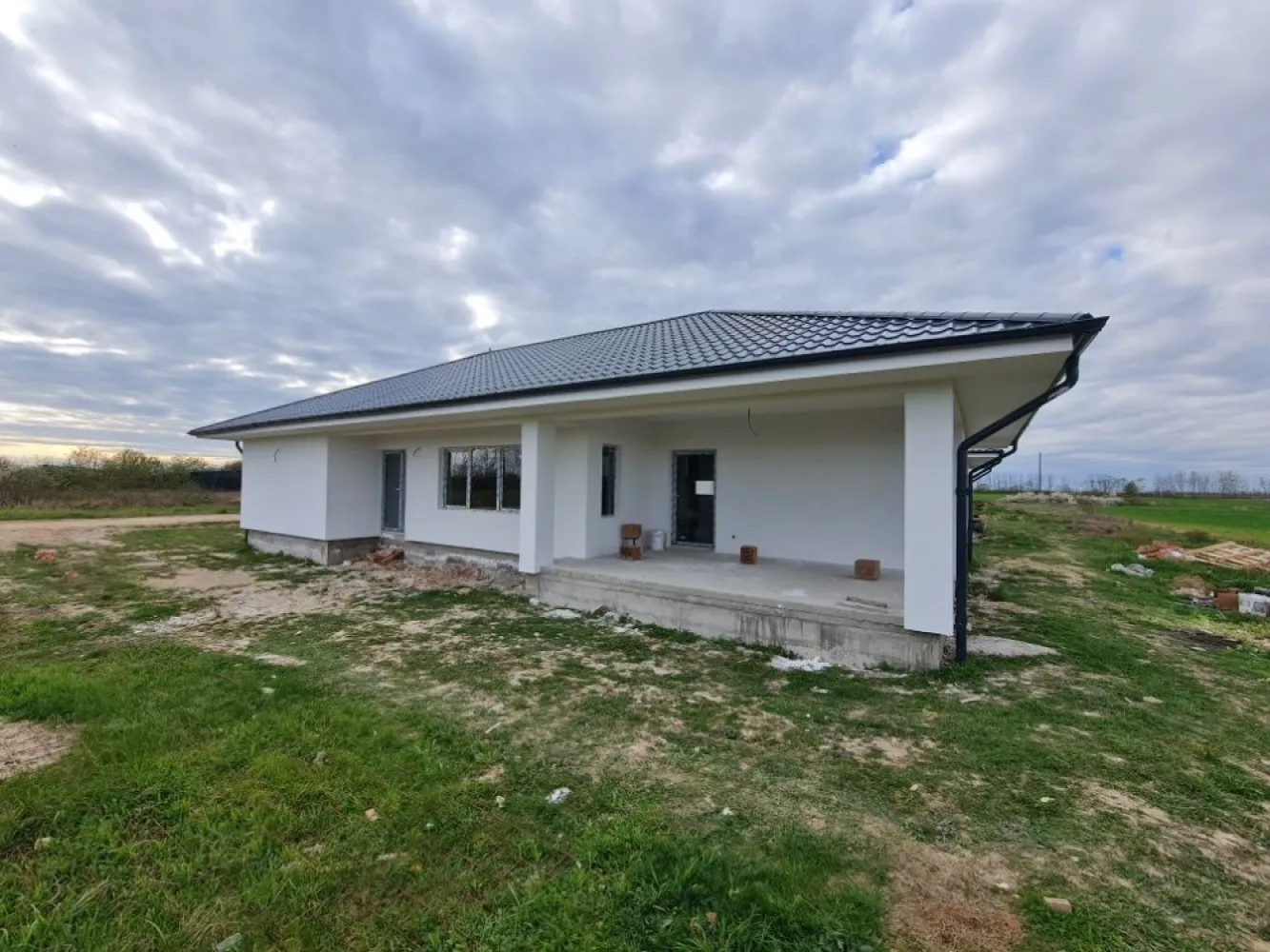 BRASADAS vinde casa noua, parter, zona Cionchesti - Agenția imobiliara BRASADAS vinde case de locuit Parter situate in loc. Cionchesti intr-o zona linistita, foarte cautata in ultima vreme, in cartier nou de case. Locatia este aproape de soseaua de centura a orasului Satu Mare, fiind foarte usor accesibila. Casele dispun de 600 mp teren fiecare, sunt optimizate functional astfel incat sa raspunda si celor mai exigente cerinte. Cu o suprafata construita de 125,00 mp la care se adauga o terasa generoasa de aproape 20 mp, planimetria este compusa dintr-o zona de zi cu living, bucatarie, camara, doua dormitoare cu baie care sa le deserveasca si separat cu acces spre terasa un dormitor matrimonial si cea de-a doua baie. Cu acces din exterior casa dispune de incapere separata pentru centrala termica. Pretul afisat este pentru stadiul la "semi-finisat" Imobilul se preda la stadiul de finisat in exterior si semifinisat in interior (realizat 1 strat glet si sapa de beton) pentru pretul de 83.500 euro Descriere constructiva: - Fundatii continue din beton armat, - Structura din zidarie portanta realizata din caramida cu goluri verticale, termoizolanta, confinata cu elemente de beton armat cu rol antiseismic - Sarpanta de lemn, ignifugata, invelitoare din tigla metalica - Izolatii termice exterioare cu polistiren Austrotherm anti foc EPS80 + extrudat XPS in zona golurilor pentru ferestre si usi - Izolatii termice in zona de pod cu vata minerala 15 cm grosime, si polistiren extrudat la pardoseala de sub cota +/-0.00 - Incalzire in pardoseala - Tamplarie din PVC Rehau cu geam termoizolant, colorate (int+ext) aspect gri antracit. Lucrarile de executie sunt bine documentante inclusiv cu fotografii, respectand cu strictete normativele romanesti si europene privind executia cladirilor.