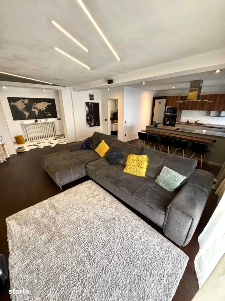 BRASADAS vinde ap 3 cam modern 106mp. mobilat, utilat, garaj. - Apartament spațios și elegant, situat pe strada Eugen Ionesco nr. 101, una dintre cele mai căutate zone rezidențiale din Cluj-Napoca, la doar 3 km de centru. Zona oferă tot ce ai nevoie la câțiva pași: stație de autobuz și easybox chiar în fața blocului, iar la 5 minute de mers pe jos se află Mega Image, Moldovan, farmacie și Profi.Locuința are 106,32 mp utili, completată de un balcon semi-închis de 4,5 mp și o terasă de 17,5 mp, acoperită, orientată spre sud și amenajată cu gazon artificial. Se vinde complet mobilată și utilată, cu electrocasnice moderne achiziționate în 2025 – un apartament pregătit pentru mutare imediată, fără nicio investiție suplimentară.Zona de zi, de peste 40 mp, include un living luminos și o bucătărie open-space, cu baie de oaspeți. Finisajele sunt premium – parchet triplu stratificat din stejar, lumini ambientale și o zonă de bar ce se poate transforma în masă de dining. Bucătăria este generoasă și complet echipată, iar din living și de pe balcon se deschide o frumoasă priveliște asupra orașului.Dormitorul matrimonial (22 mp) include dressing separat de 9,2 mp, birou, aer condiționat smart și acces direct la terasa însorită, perfectă pentru relaxare sau pentru plante ornamentale și aromatice. Baia principală (6,65 mp) este echipată cu produse Grohe, Kludi și Geberit, are încălzire în pardoseală, fereastră și walk-in shower spațios. Dormitorul secundar (15,56 mp), orientat estic, este ideal pentru copii sau oaspeți, dotat cu birou și lumini ambientale.Sistemul de încălzire este pe gaz, cu control smart Netatmo, iar iluminatul se face prin Philips Hue. Apartamentul este prevăzut cu senzori de securitate, internet fibră optică și folie privacy pe o parte din geamuri.Include două locuri de parcare în garajul subteran – unul proprietate și unul cu chirie redusă. Ambele sunt foarte spațioase, potrivite și pentru depozitare, dotate cu siguranță separată și prize 220V simple și industriale (ideal pentru mașini electrice).Imobilul are doar 6 apartamente și dispune de o grădină comună privată, folosită ca loc de joacă și zonă de relaxare. Comunitatea este liniștită și prietenoasă.Str. Eugen Ionesco 101, Cluj-NapocaComplet mobilat și utilat – electrocasnice 2025106,32 mp utili + terasă 17,5 mp + balcon 4,5 mpDouă locuri de parcare (1 proprietate + 1 chirie redusă)